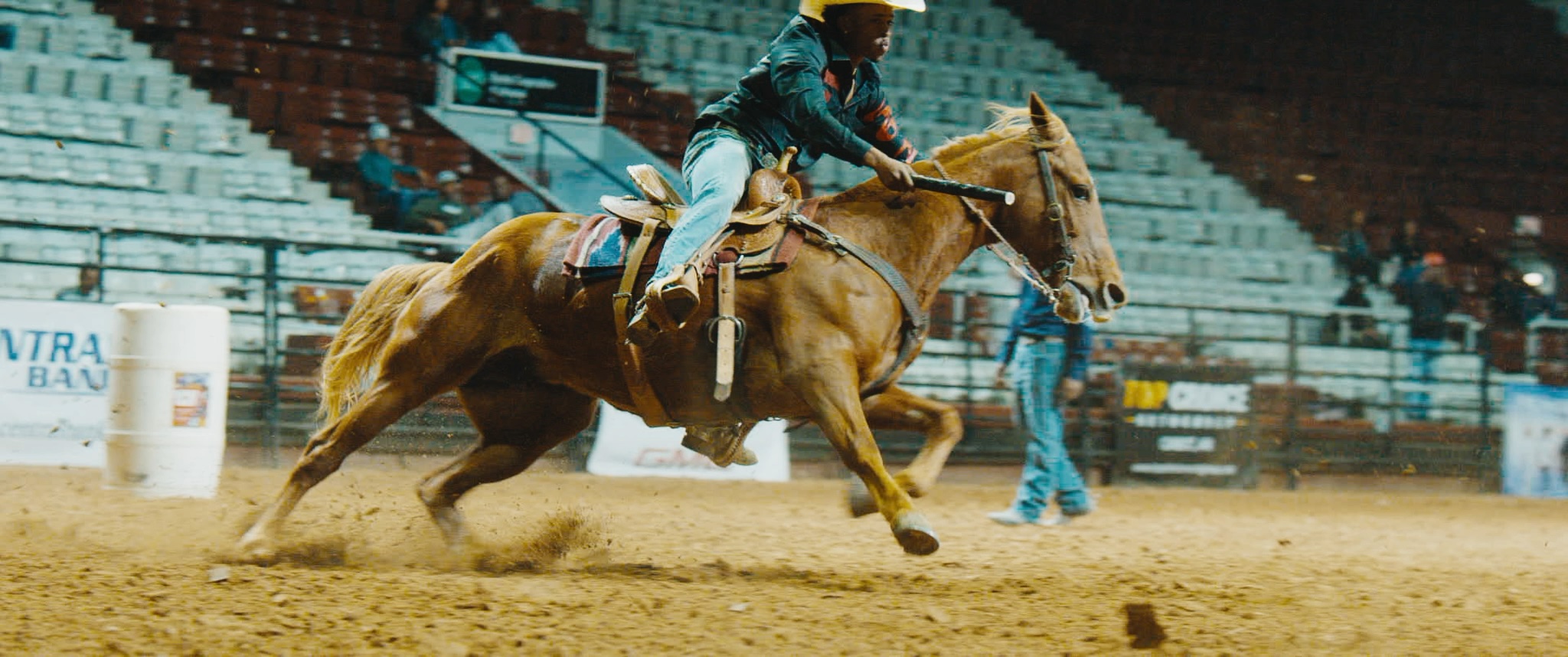 A rodeo rider and horse race through an arena.